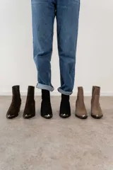 Bota corta de cuero vacuno color negro, con puntera metálica plateada, caña baja, cierre lateral y taco de 7cm. Fabricada en Uruguay.