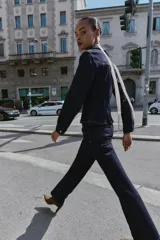 Camisa de denim color azul oscuro, de manga larga y corte entallado. Presenta cuello solapa, un bolsillo de plastrón en el pecho y cierre frontal con botones dorados.