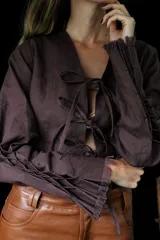 Camisa corta color rojo con escote en V y mangas largas acampanadas. Presenta ajuste frontal con lazos.