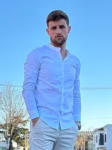 Camisa blanca de manga larga con cuello mao y cierre frontal con botones.