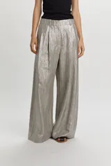 Pantalón ancho color gris metalizado, con pinzas delanteras, trabillas para cinto y cierre frontal con botón.