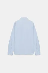 Camisa de manga larga con patrón de rayas verticales en tonos celeste y blanco, cuello con solapa abotonada y un bolsillo aplicado en el pecho. Cierre frontal con botones blancos.