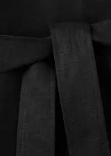 Chaqueta de lino color negro con diseño recto, cuello camisero, manga larga, cierre frontal de botones y cinturón ajustable del mismo material. Incluye forro interior.