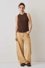 Blusa tejida sin mangas en color marrón chocolate, con textura acanalada, cuello redondo y detalle de flecos en el ruedo.