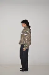 Campera de jogging con estampado de camuflaje tipo Real Tree, corte oversize y cierre frontal. Presenta un detalle de puntilla blanca en la parte superior delantera y un bordado a tono en el pecho.