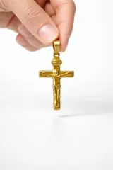 Dije de cruz con figura de Cristo en relieve, fabricado en acero con acabado dorado brillante.