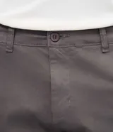 Pantalón slim de sarga lavada color marrón, con cierre de botón y cremallera, trabillas para cinturón y bolsillos laterales y traseros.