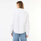 Blusa blanca de manga larga con cuello alto con volantes y cierre frontal de botones con ribetes dorados.