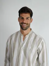 Camisa de manga larga con cuello mao, confeccionada en tela a rayas verticales en tonos blanco y beige. Presenta cierre frontal con botones y logo bordado en el pecho.