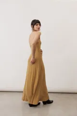 Vestido largo negro de corte al cuerpo con cuello halter y detalle de hebilla metálica dorada en el hombro con tira drapeada.