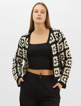 Cardigan abierto de tejido de punto calado con diseño geométrico bicolor en mangas y paneles frontales, y espalda en tono sólido. Presenta silueta recta, frente abierto sin cierre y terminaciones con vivos reforzados en escote, puños y ruedo.