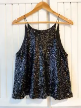 Musculosa negra cubierta de lentejuelas brillantes, con breteles finos y corte holgado.