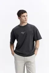 Remera de manga corta color beige, con escote redondo y estampado frontal con la palabra "Surreal" en tipografía cursiva.