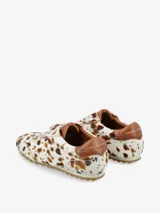 Zapatilla de estilo urbano con diseño de silueta clásica, confeccionada en cuero con textura de pelo natural y estampado animal print. Presenta cierre con cordones, refuerzo en el talón y suela dentada.