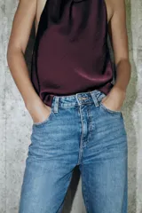 Jeans de tiro alto con corte mom fit, diseño de cinco bolsillos y detalle de raya planchada frontal. Cierre frontal con cremallera y botón.