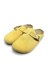 Zuecos de gamuza color amarillo, diseño cerrado en la parte delantera y destalonado, con una tira superior ajustable mediante hebilla metálica.
