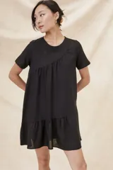 Vestido negro corto con cuello redondo, mangas cortas y falda con volantes.