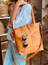 Bolso tipo tote bag color suela, de cuero, con doble asa de mano y correa larga extraíble y ajustable. Tiene dos bolsillos externos grandes.