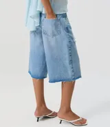 Bermuda jorts de jean en color celeste, con cintura media, calce amplio, bolsillos delanteros y traseros, y detalles de desgastes localizados.