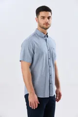 Camisa de manga corta confeccionada en mezcla de lino y algodón, con estampado de cuadros pequeños en tonos azules. Presenta cuello camisero con botones, cierre frontal abotonado, bolsillo aplicado en el pecho y dobladillo redondeado.