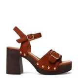 Sandalias de tacón alto Miss Carol modelo Torino, confeccionadas en gamuza marrón. Presentan plataforma con efecto de madera, taco ancho y tira en el empeine con hebilla metálica dorada y tachas decorativas. Incluyen tira ajustable al tobillo con hebilla.