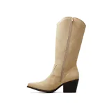 Bota estilo texana de caña alta, confeccionada en gamuza negra. Presenta un diseño clásico con costuras decorativas, punta fina y un taco cuadrado de altura media. Incluye un detalle metálico con la letra V en la parte superior de la caña.