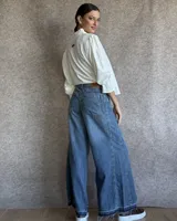 Pantalón de jean azul de tiro medio, con corte wide leg y ruedo deshilachado.