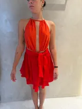 Falda corta de color rojo intenso, con diseño de volados escalonados y cintura alta con lazo ajustable para anudar al frente.