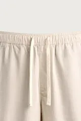 Pantalón de corte regular fit confeccionado en tejido mezcla de algodón, con cintura elástica ajustable mediante cordón, bolsillos laterales y bolsillos traseros de vivo.