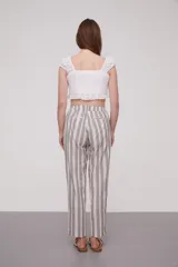 Pantalón babucha celeste con rayas verticales blancas, cintura elástica con cordón y detalle de borlas.