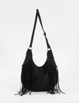 Cartera bandolera de estilo boho con flecos largos en los laterales. Cuenta con una correa ajustable con hebilla y herrajes metálicos en tono bronce.