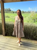 Vestido celeste de lino, sin mangas, con cuello mao y botones de nácar. Presenta varios cortes en su largo, aportando movimiento y un toque moderno a este diseño fresco y elegante.