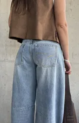 Jean de denim celeste de corte barrel, tiro bajo, con roturas y detalles desgastados en la rodilla.