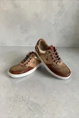 Championes de cuero en tonos marrones y beige combinados, con texturas y detalles pintados a mano por Carolina De Cunto, suela de goma blanca y cordones marrones.