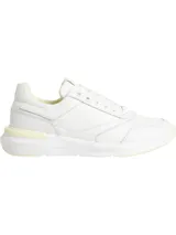 Zapatillas deportivas blancas con cordones, confeccionadas en una mezcla de cuero natural, cuero ecológico y textil. Presentan un diseño con monograma sutil en el lateral y detalles en tono amarillo pálido en la suela y el talón.