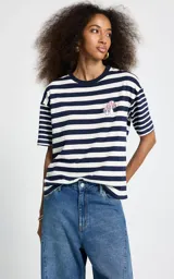 Remera de manga corta con diseño a rayas horizontales en azul marino y blanco, confeccionada en algodón. Presenta un pequeño bordado de hongos en el pecho y cuello redondo.
