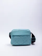 Bandolera rectangular color celeste, confeccionada en nylon reciclado con capitoneado ondulado. Cuenta con un bolsillo externo, uno interno y una correa regulable negra.