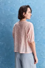 Blusa de manga corta color rosado con estampa orgánica de inspiración floral, cuello redondo y ajuste mediante lazo en el ruedo.