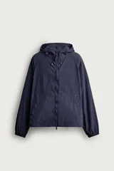 Cazadora cortavientos de corte relaxed fit, color azul marino con patrón de cuadros sutil tipo ripstop. Cuenta con capucha ajustable con cordón, cierre frontal de cremallera de doble dirección, bolsillos frontales y puños con elástico.
