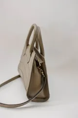 Cartera mediana color verde oliva, de cuero con diseño acolchado con pespuntes ondulados. Tiene doble asa corta y correa larga desmontable.