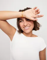 Pulsera de hilo color naranja con perla shell y fornitura bañada en oro de 18k.