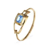 Pulsera semirrígida bañada en oro 18k con diseño orgánico y cristal azul facetado de corte rectangular en el centro.