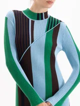 Vestido midi de punto acanalado con cuello medio alto y mangas largas. Presenta un diseño de rayas verticales en bloques de color azul, verde y marrón, con una línea diagonal decorativa que cruza el frente.