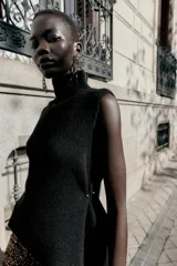 Top de punto color verde militar, con cuello subido y manga sisa. Presenta apliques dorados en los laterales y un bajo asimétrico.