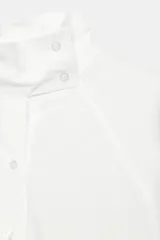 Camisa amplia blanca de cuello alto y manga larga, con cierre frontal de botones.
