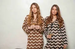 Vestido largo de lurex con diseño de patrón en zigzag en tonos tostado y marrón, escote en V con cordones para atar y mangas largas.
