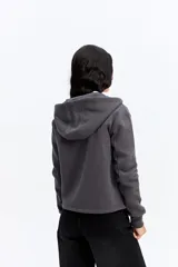 Campera tipo hoodie de algodón en color gris oscuro, con cierre frontal completo, capucha con cordones ajustables y bolsillos laterales. Presenta un diseño minimalista con logo bordado sutil en el pecho.