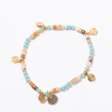 Pulsera de cuentas elásticas con piedras naturales en tonos tierra y turquesa, intercaladas con cuentas doradas cilíndricas y dijes colgantes redondos dorados.
