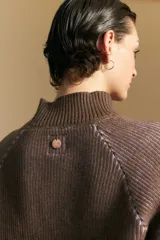 Polera de tejido acanalado en color marrón con detalles de líneas en tono lila, cuello alto y mangas largas con diseño raglán.