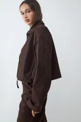 Campera corta de efecto cuero color marrón, con cuello solapa, cierre frontal y diseño de estructura ligera.
